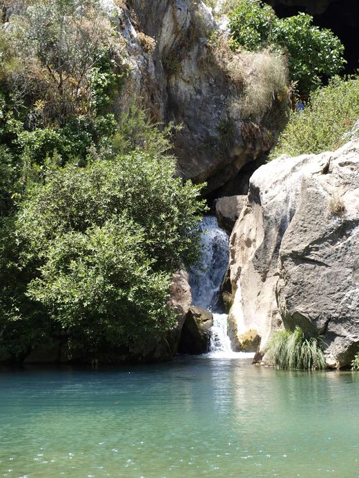 Cascada de la Cueva del Gato cayendo a una poza de agua turquesa